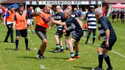 Eamonn Twamley Players take part in the Kingswood Walking Rugby Championships. One team is wearing blue and white hooped tops while the other is wearing orange bibs