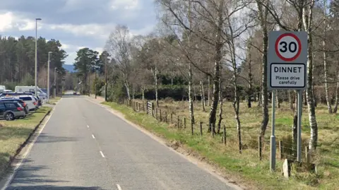 Google road into dinnet with street sign and trees