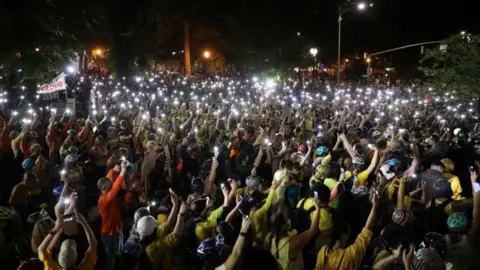 Reuters As part of a peaceful demonstration in the city on Monday evening, thousands of protesters walked through the streets holding aloft lit mobile phones