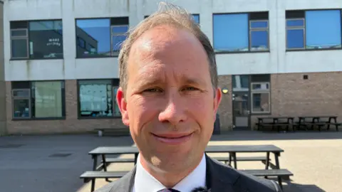 Chris McHugh / BBC Matthew Barber poses for a photo. He has thinning hair, clean shaven ands wearing a white smart shirt and black jacket.