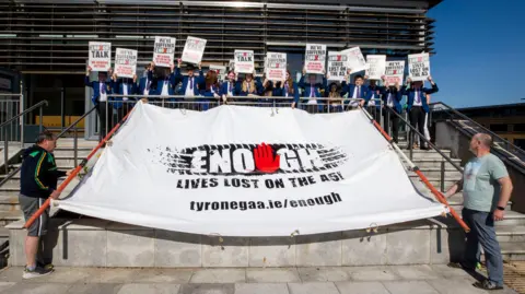 PA Media Students and staff from Sacred Heart College in Omagh, holding placards, with supporters of the Enough is Enough group in May 2023