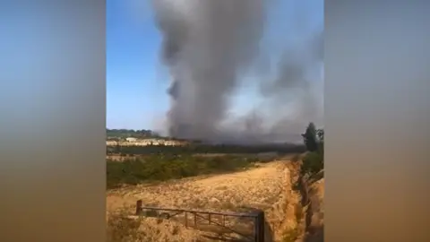 Dark smoke rising into a bluw sky from a heath fire