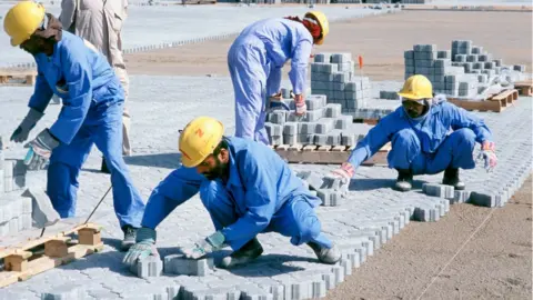 Getty Images Construction workers laying block paving for container stacking areas, Dubai port Jebel Ali, UAE.