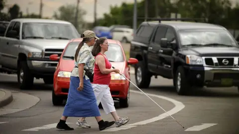 Joe Amon/Getty Images Janet Barlow offers guidance to Shelley Bruns crossing the street in Denver