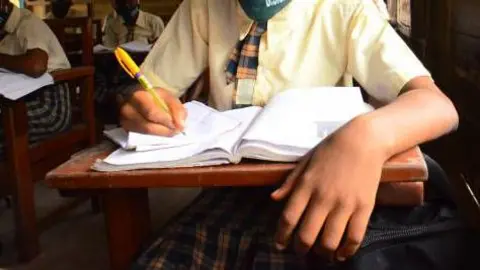 A high school female student in Nigeria writing on a book