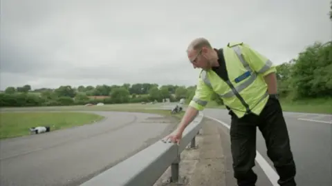man pointing at abrasive mark on a barrier 
