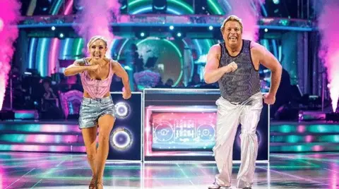 Guy Levy/BBC/PA Wire Amy and Thomas wearing dance outfits dancing on as lit up set