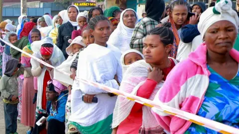 Reuters A queue of women voters stand alongside some plastic tape marking the queue.