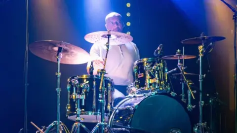 Lionel Duke performs on stage as he plays the drums