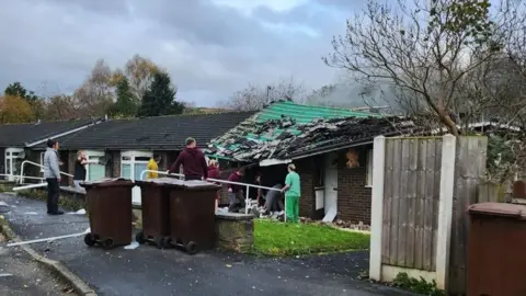 People outside a collapsed bungalow