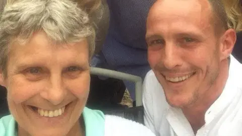 Jordan Findlay A middle aged woman with greying, short hair, pictured with a young man who looks like her son. They are both smiling.