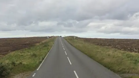 Google An empty road in an empty isles landscape. The sky is grey.