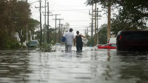 AFP/gETTY A couple wade through a flooded Key West street in aftermath of Wilma