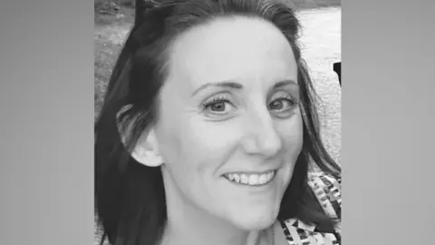 Emma A close-up black and white photo of a woman's face as she smiles at the camera. 