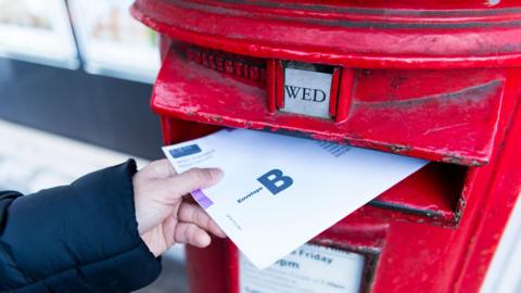 Postal vote being dropped into a postbox 