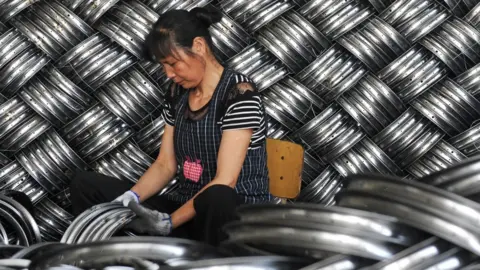 Getty Images A woman works in a factory making steel hubs in China