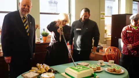 PA Media Queen Camilla cuts a cake with the sword from the Lord-Lieutenant of the County and City of Bristol