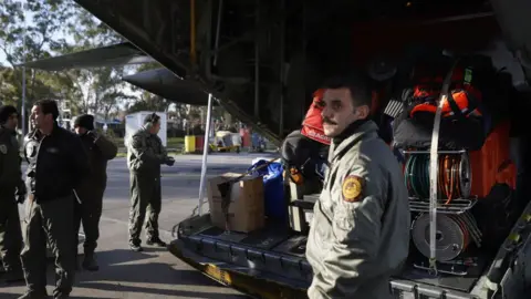 Getty Images A Greek soldier stands near a plane being loaded with supplies