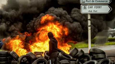 AFP A fishermen from the French city of Boulogne walks past burning tyres blocking access to the port of Boulogne-sur-Mer on January 25, 2018,