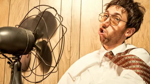 Getty Images a man trying to cool down with a fan