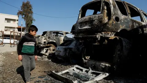 Reuters A Palestinian child walks near cars burnt near Hawara