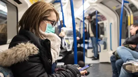 PA Media Woman wearing face mask on Tube