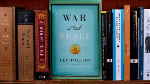 Getty Images Uma edição azul esverdeada de Guerra e Paz, de Leo Tolstoy, aparece em uma estante com outras edições do romance ao lado