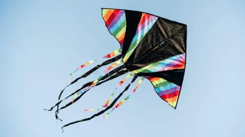 Getty Images A colourful kite flying in the blue sky.