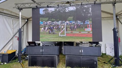 A big screen and speakers under a white canopy