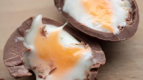 BBC Cadbury's Creme Egg cut in half on a wooden table