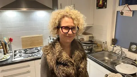 Phil Harrison/BBC A blonde woman standing in her kitchen.