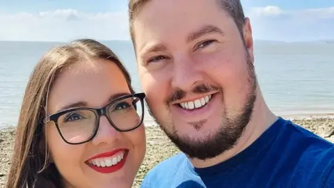 Julian Morgan Julian and his partner smile in a selfie on a beach 