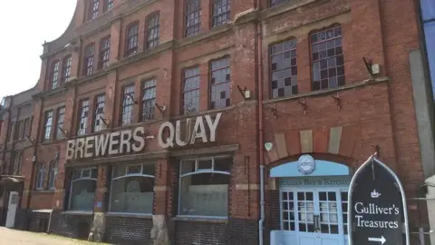 The old Brewers Quay building. It is a large red brick brewery with a sign reading Brewers Quay.