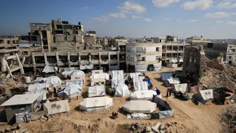 Reuters tents for displaced Palestinians are established almost destroyed and very damaged buildings in Gaza City (February 26, 2025)