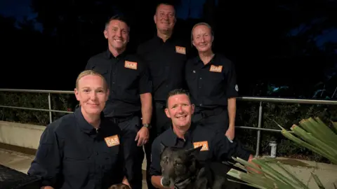 Lancashire Fire and Rescue Service Five firefighters in black uniforms smiling.