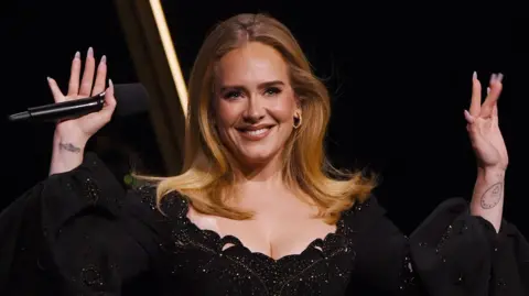 Adele smiling on stage with both hands raised during her final Las Vegas residency show "Weekends with Adele", at The Colosseum at Caesars Palace on November 23, 2024