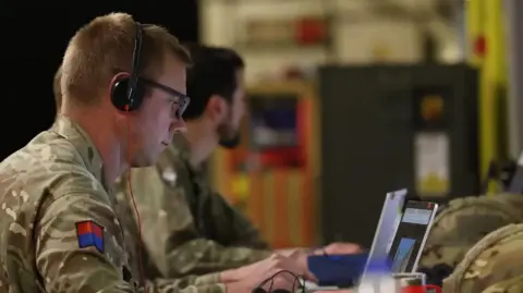 British Army Two army soldiers sit at laptops in a disused area of a London Underground station