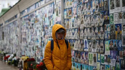 Getty Images A person walks past The Wall of Remembrance of the Fallen for Ukraine in Kyiv on February 25, 2026.