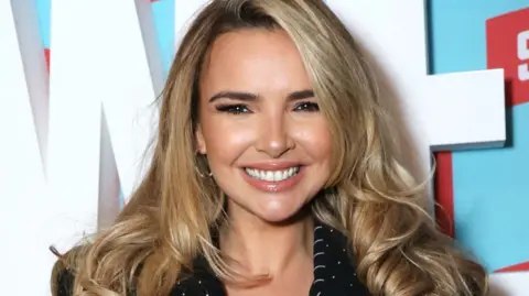 Getty Images Nadine Coyle smiling to the camera - she has long blonde hair