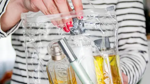 Getty Images Woman putting bottles of liquid into a clear plastic bag in order to pass through airport security