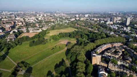 Aerial view of Primrose Hill showing parkland with trees alongside local housing. 