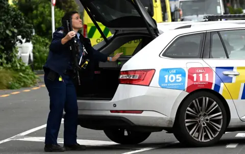 AFP via Getty Images A police officer holding a gun which has been taken from a locked box in the boot of a police car