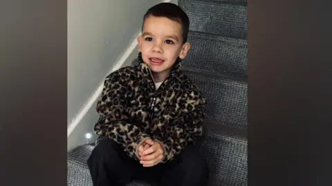 Kendra Hazlett A boy in a fleece sitting on stairs