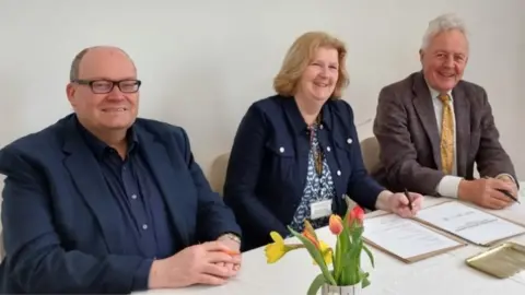 Cornwall Council Darren Henley, Chief Executive or Arts Council England, Councillor Carol Mould, portfolio holder for Neighbourhoods at Cornwall Council, and Duncan Wilson, Chief Executive of Historic England, sign the Memorandum of Understanding