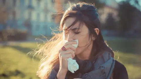 Getty Images Woman holding a tissue to her nose