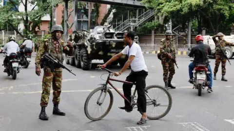 Reuters police and people on the streets of Dhaka on Sunday 21 July