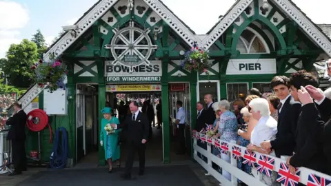 PA Media Queen Elizabeth II accompanied by Bill Bewley, Chairman of Windermere Lake Cruises arrives at Bowness on Windermere Pier, Cumbria, North West England on 17 July 2013