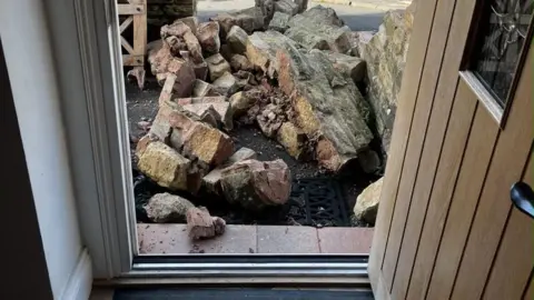 Supplied A front door opened from the inside with a pile of bricks outside the door. 