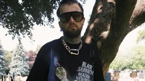 Mason Newman Artist Mason Newman wears a t-shirt with Black Sabbath Mason Newman on it