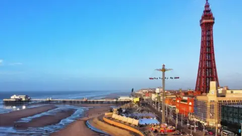 PA Media An image of Blackpool seafront. The tower is on the right-hand side of the photo, and the north pier, jutting out to sea, is on the left.
